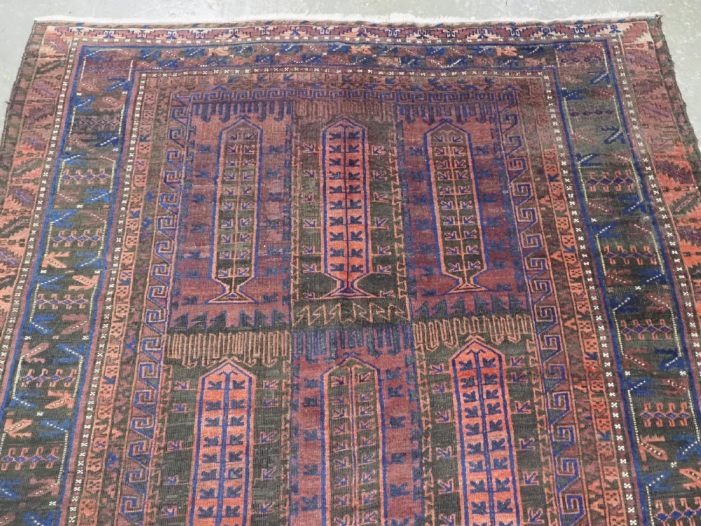 A late nineteenth-century hand-knotted wool Baluch carpet featuring repeated geometric column motifs in indigo, dark red, and purple shades within multiple patterned borders. View III