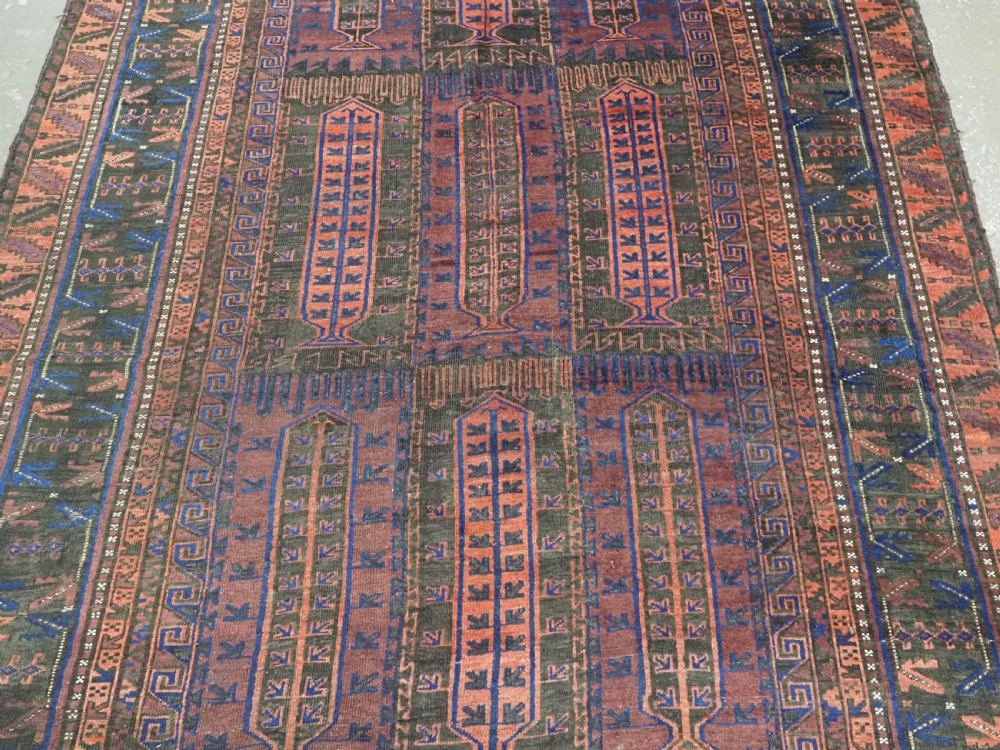 A late nineteenth-century hand-knotted wool Baluch carpet featuring repeated geometric column motifs in indigo, dark red, and purple shades within multiple patterned borders. View IV