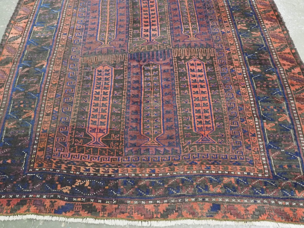 A late nineteenth-century hand-knotted wool Baluch carpet featuring repeated geometric column motifs in indigo, dark red, and purple shades within multiple patterned borders. View V