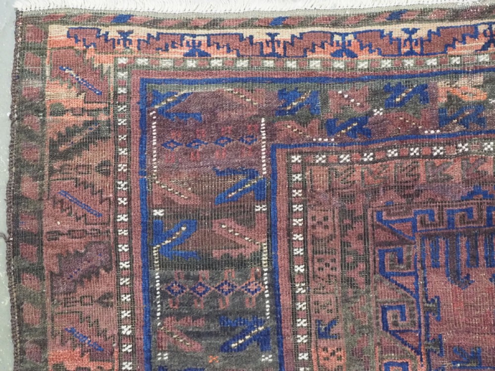 A late nineteenth-century hand-knotted wool Baluch carpet featuring repeated geometric column motifs in indigo, dark red, and purple shades within multiple patterned borders. View VI