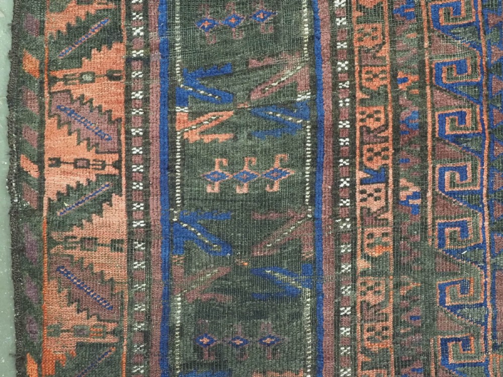 A late nineteenth-century hand-knotted wool Baluch carpet featuring repeated geometric column motifs in indigo, dark red, and purple shades within multiple patterned borders. View VII