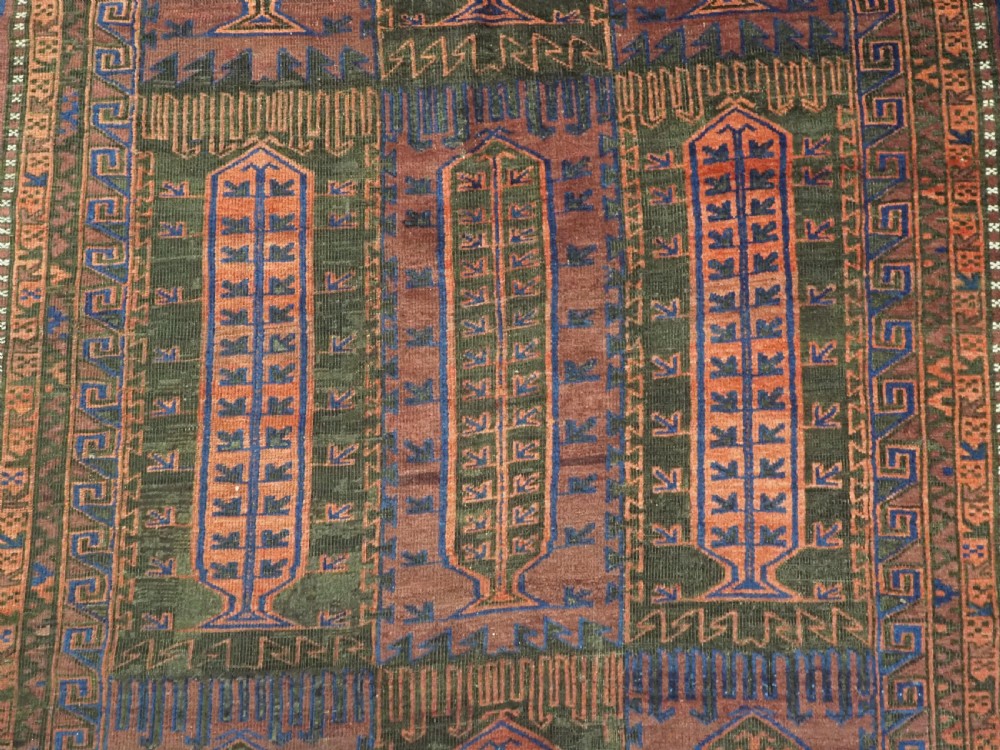 A late nineteenth-century hand-knotted wool Baluch carpet featuring repeated geometric column motifs in indigo, dark red, and purple shades within multiple patterned borders. View IX