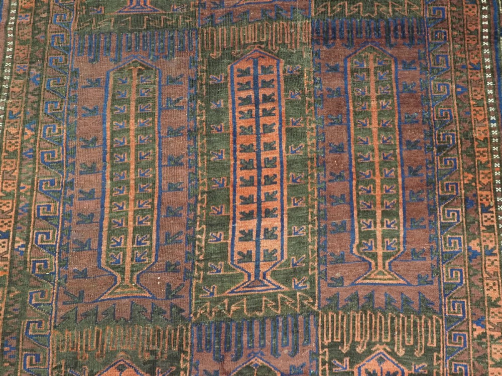 A late nineteenth-century hand-knotted wool Baluch carpet featuring repeated geometric column motifs in indigo, dark red, and purple shades within multiple patterned borders. View X