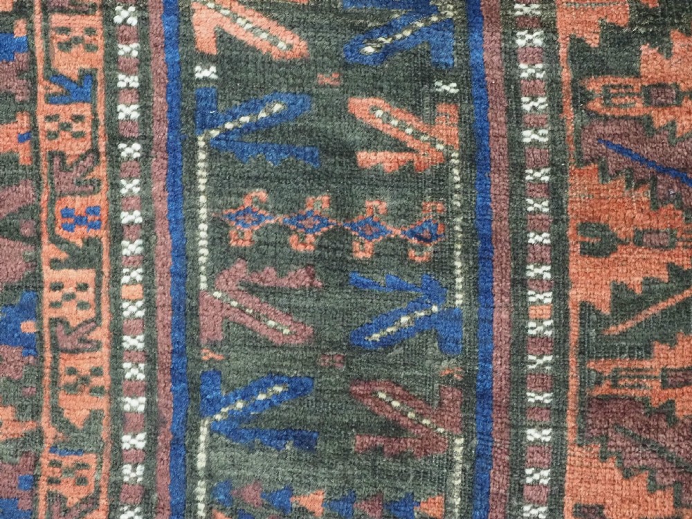 A late nineteenth-century hand-knotted wool Baluch carpet featuring repeated geometric column motifs in indigo, dark red, and purple shades within multiple patterned borders. View XII