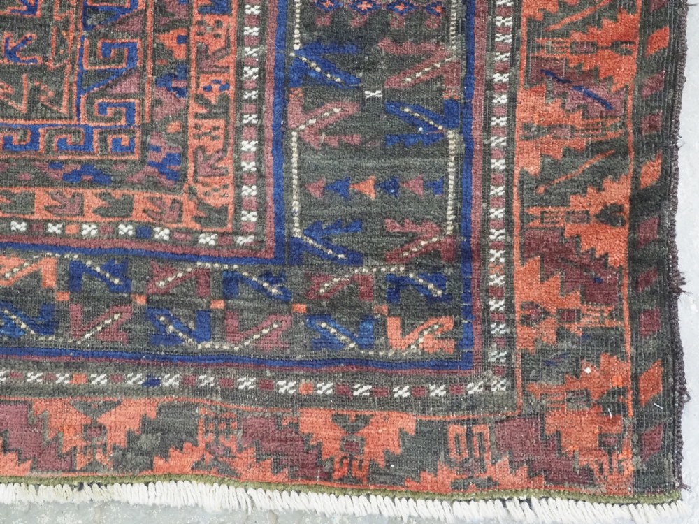 A late nineteenth-century hand-knotted wool Baluch carpet featuring repeated geometric column motifs in indigo, dark red, and purple shades within multiple patterned borders. View XIII