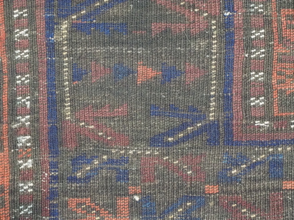 A late nineteenth-century hand-knotted wool Baluch carpet featuring repeated geometric column motifs in indigo, dark red, and purple shades within multiple patterned borders. View XIV