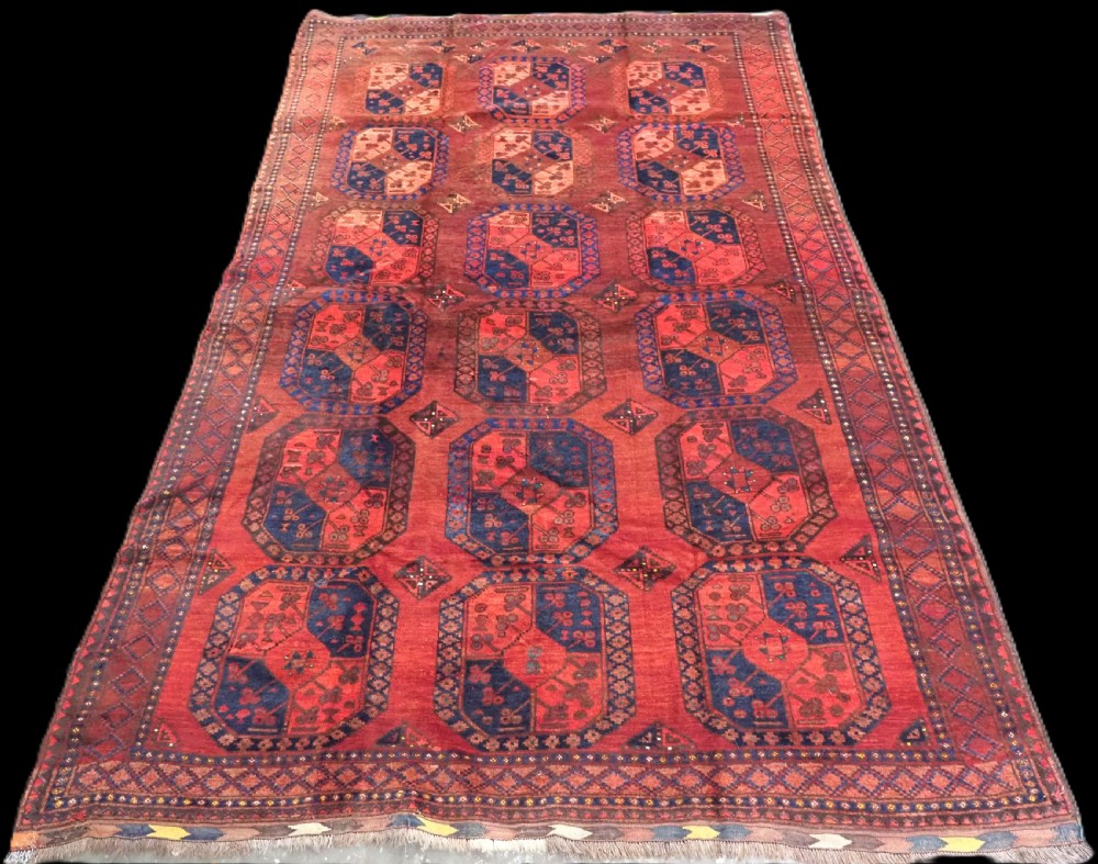 An antique hand-knotted Ersari Turkmen wool carpet featuring repeating octagonal gul medallions on a deep red field with geometric borders.