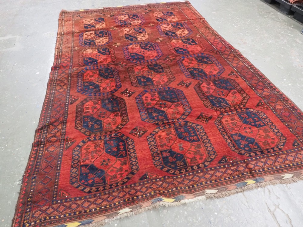 An antique hand-knotted Ersari Turkmen wool carpet featuring repeating octagonal gul medallions on a deep red field with geometric borders. View II