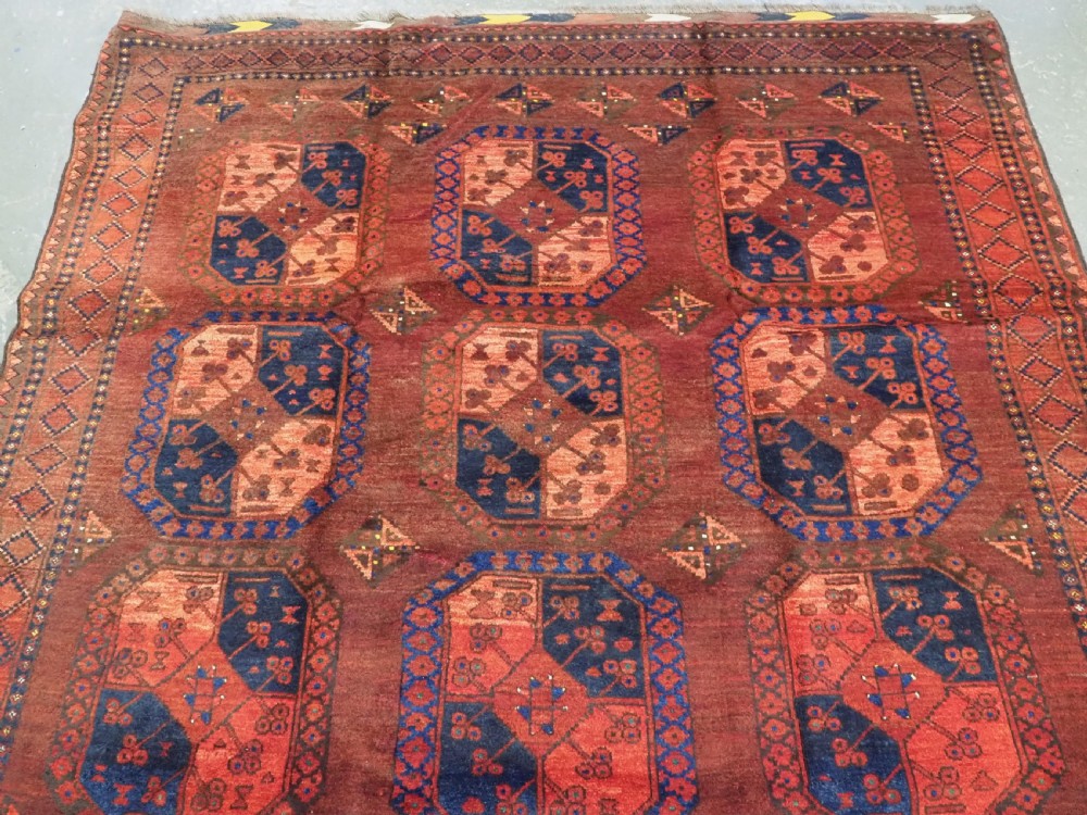 An antique hand-knotted Ersari Turkmen wool carpet featuring repeating octagonal gul medallions on a deep red field with geometric borders. View III