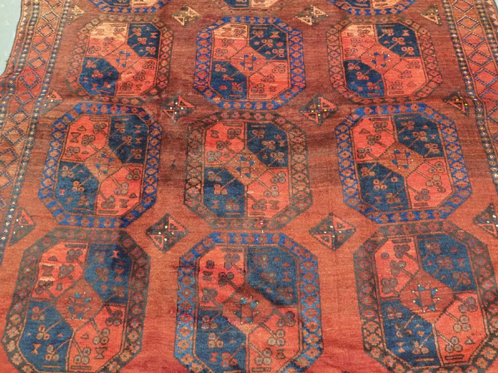 An antique hand-knotted Ersari Turkmen wool carpet featuring repeating octagonal gul medallions on a deep red field with geometric borders. View IV