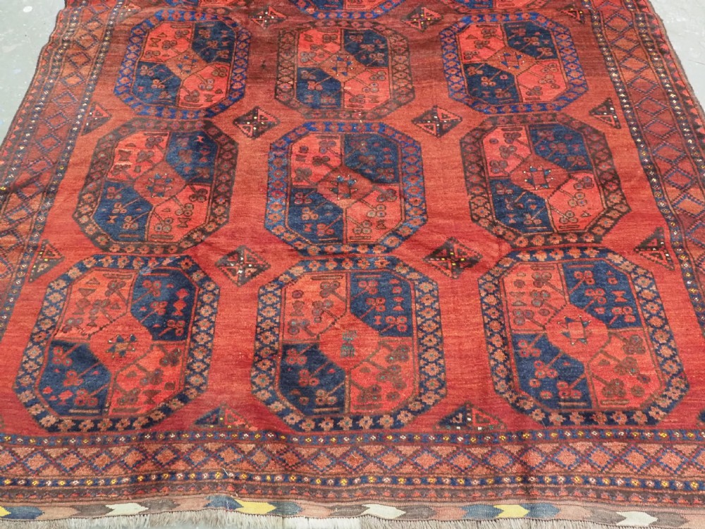 An antique hand-knotted Ersari Turkmen wool carpet featuring repeating octagonal gul medallions on a deep red field with geometric borders. View V