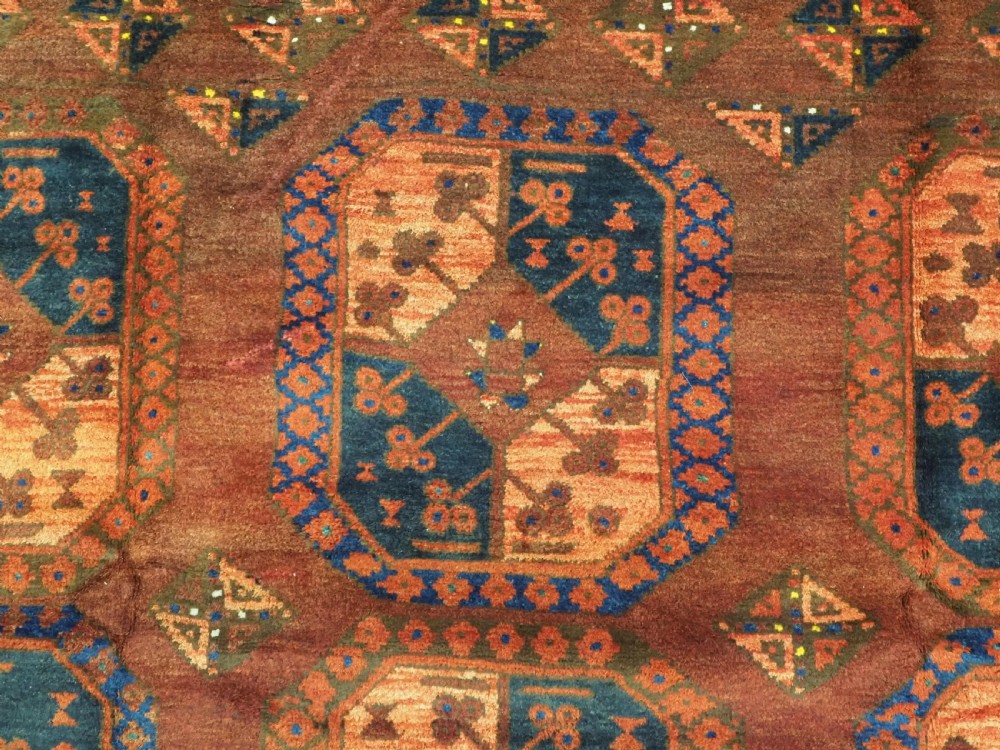 An antique hand-knotted Ersari Turkmen wool carpet featuring repeating octagonal gul medallions on a deep red field with geometric borders. View VIII