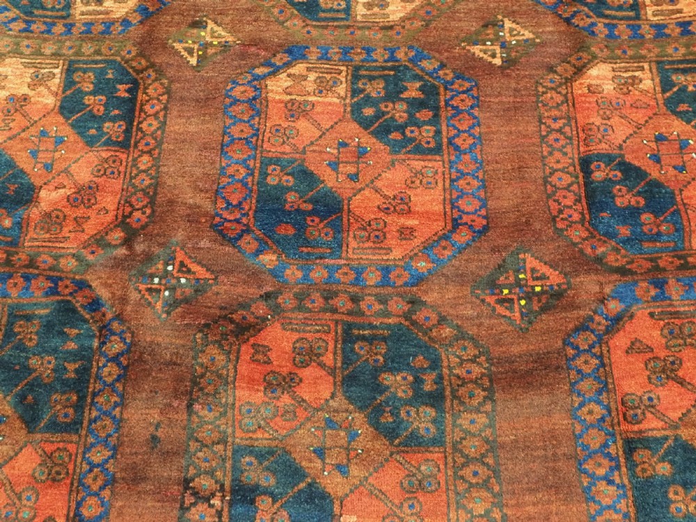 An antique hand-knotted Ersari Turkmen wool carpet featuring repeating octagonal gul medallions on a deep red field with geometric borders. View IX