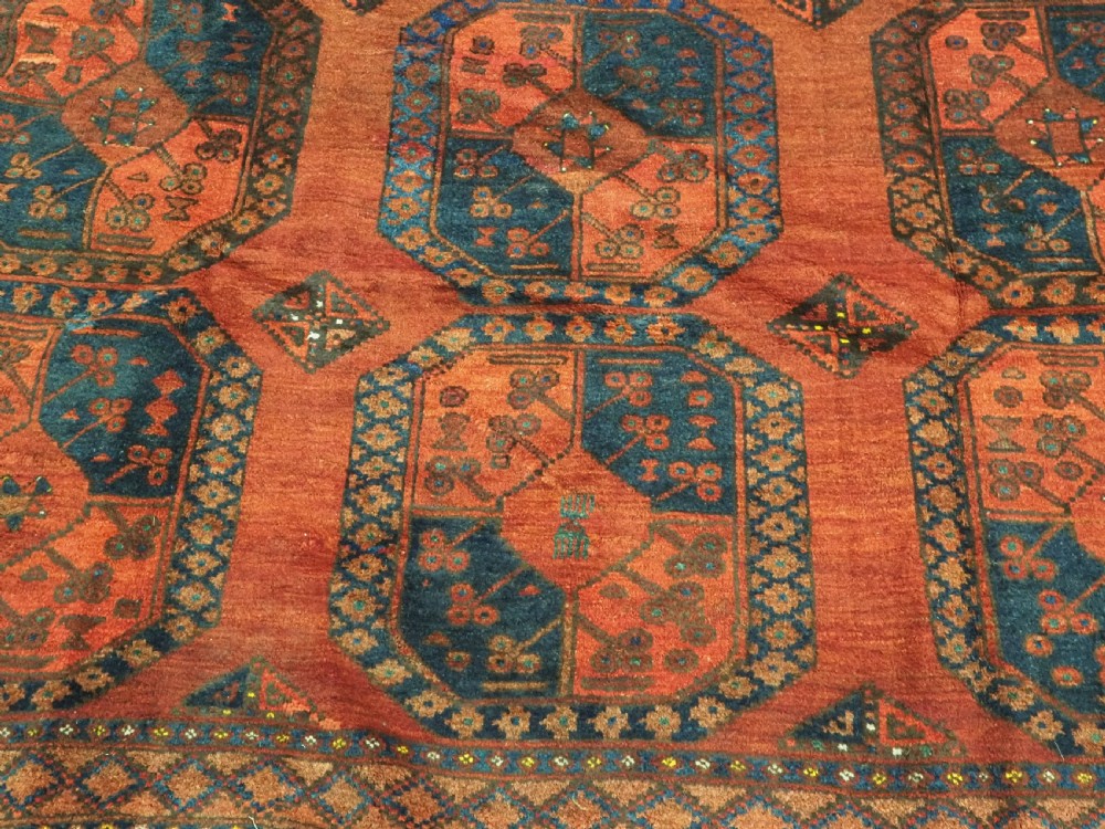 An antique hand-knotted Ersari Turkmen wool carpet featuring repeating octagonal gul medallions on a deep red field with geometric borders. View X