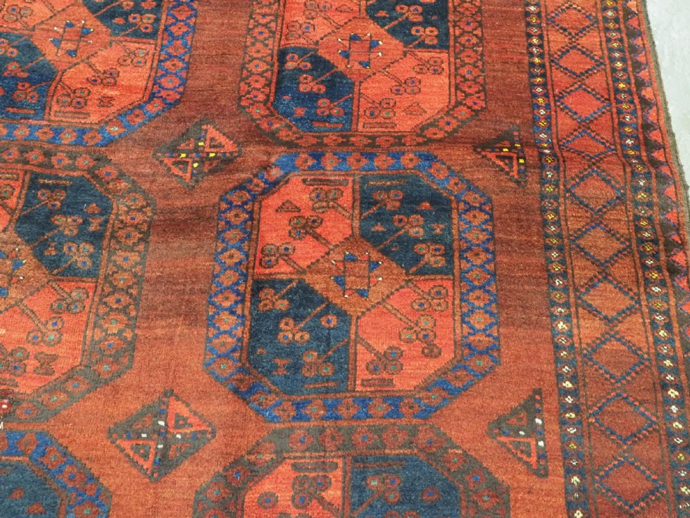 An antique hand-knotted Ersari Turkmen wool carpet featuring repeating octagonal gul medallions on a deep red field with geometric borders. View XII