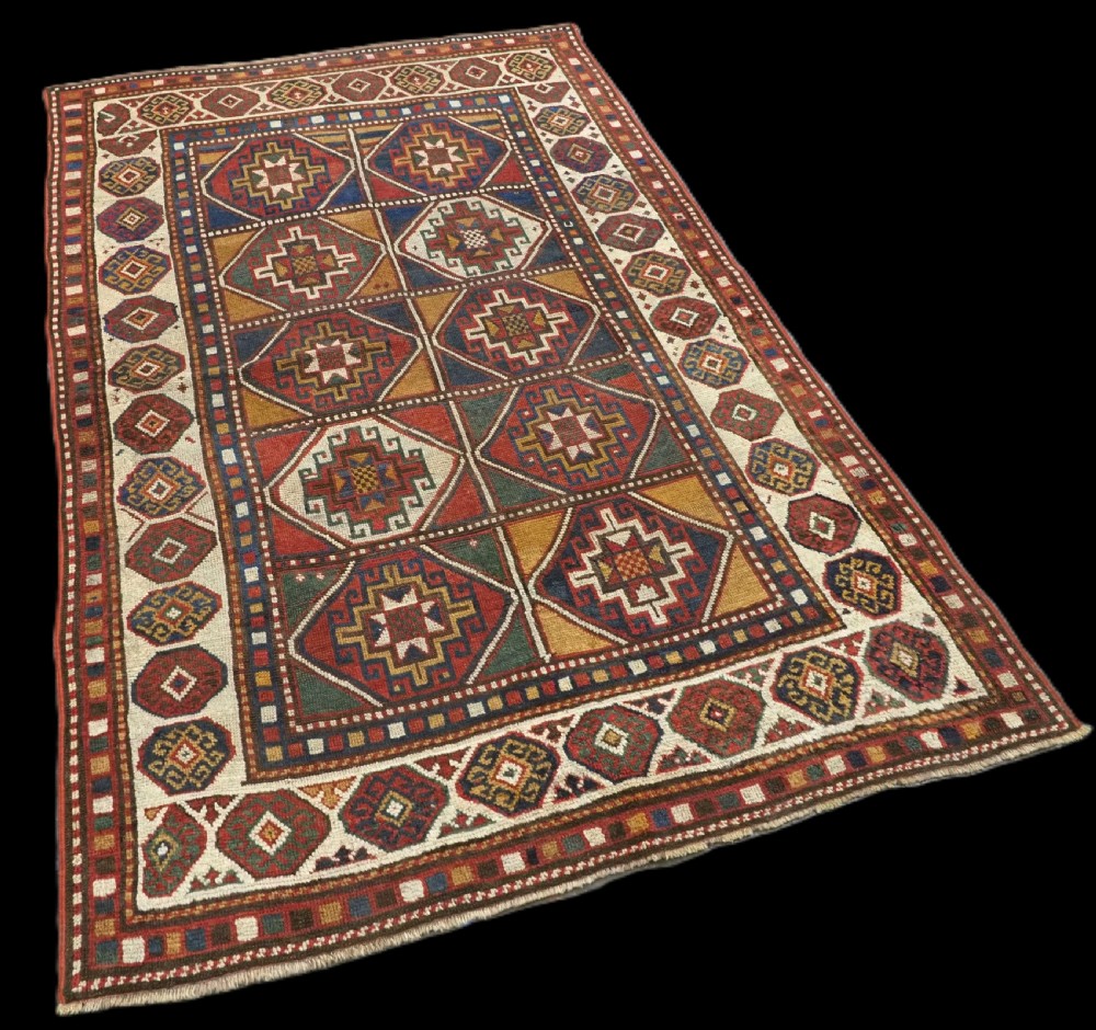 An antique hand-knotted Caucasian Moghan Kazak wool rug featuring a grid of geometric latch-hook medallions framed by patterned borders. View II