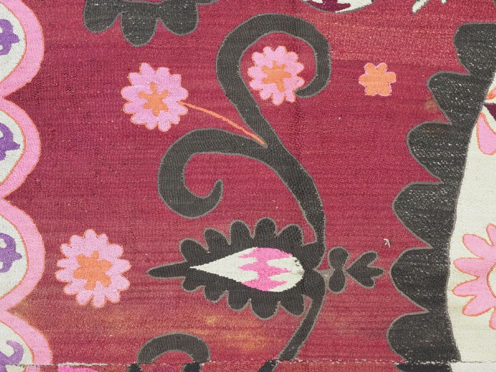A rectangular hand-embroidered textile featuring a large central circular starburst medallion surrounded by floral motifs in shades of pink, cream, orange, and burgundy. View VIII
