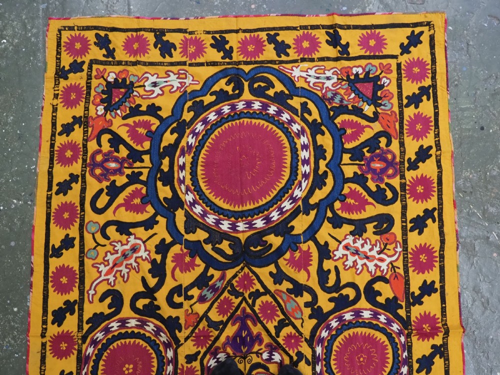 An antique Uzbek prayer suzani featuring silk embroidery with circular floral medallions and a central arch motif on a yellow cotton ground. View II