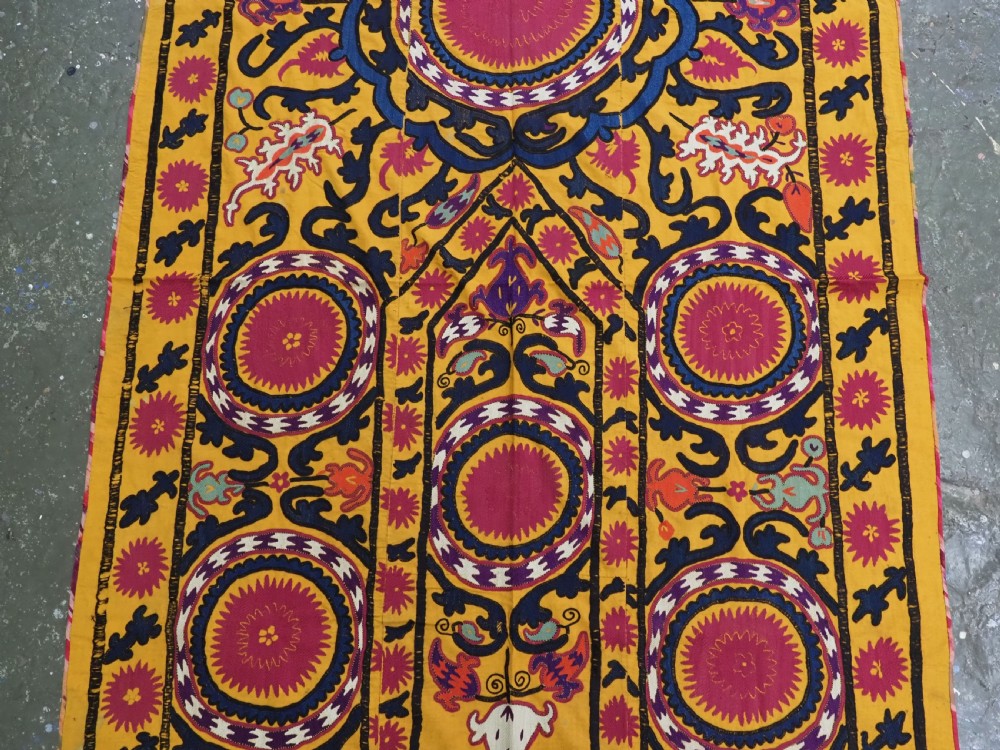 An antique Uzbek prayer suzani featuring silk embroidery with circular floral medallions and a central arch motif on a yellow cotton ground. View III