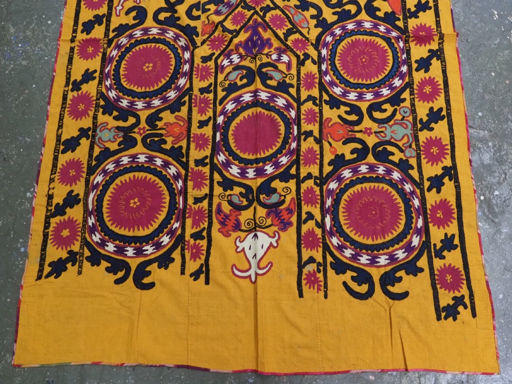 An antique Uzbek prayer suzani featuring silk embroidery with circular floral medallions and a central arch motif on a yellow cotton ground. View IV