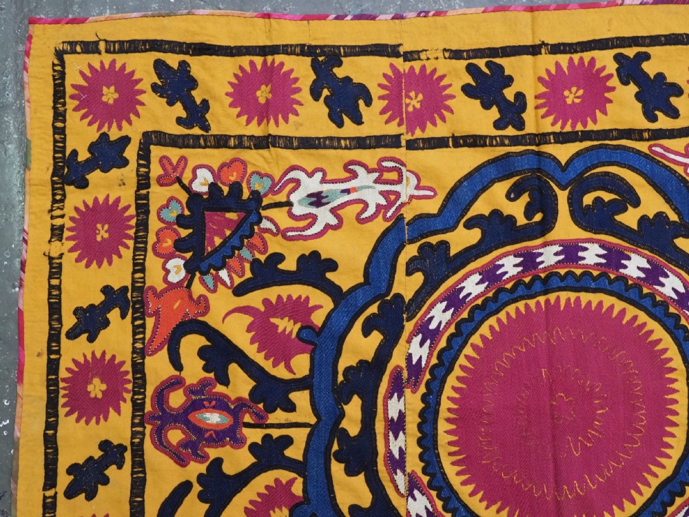 An antique Uzbek prayer suzani featuring silk embroidery with circular floral medallions and a central arch motif on a yellow cotton ground. View V