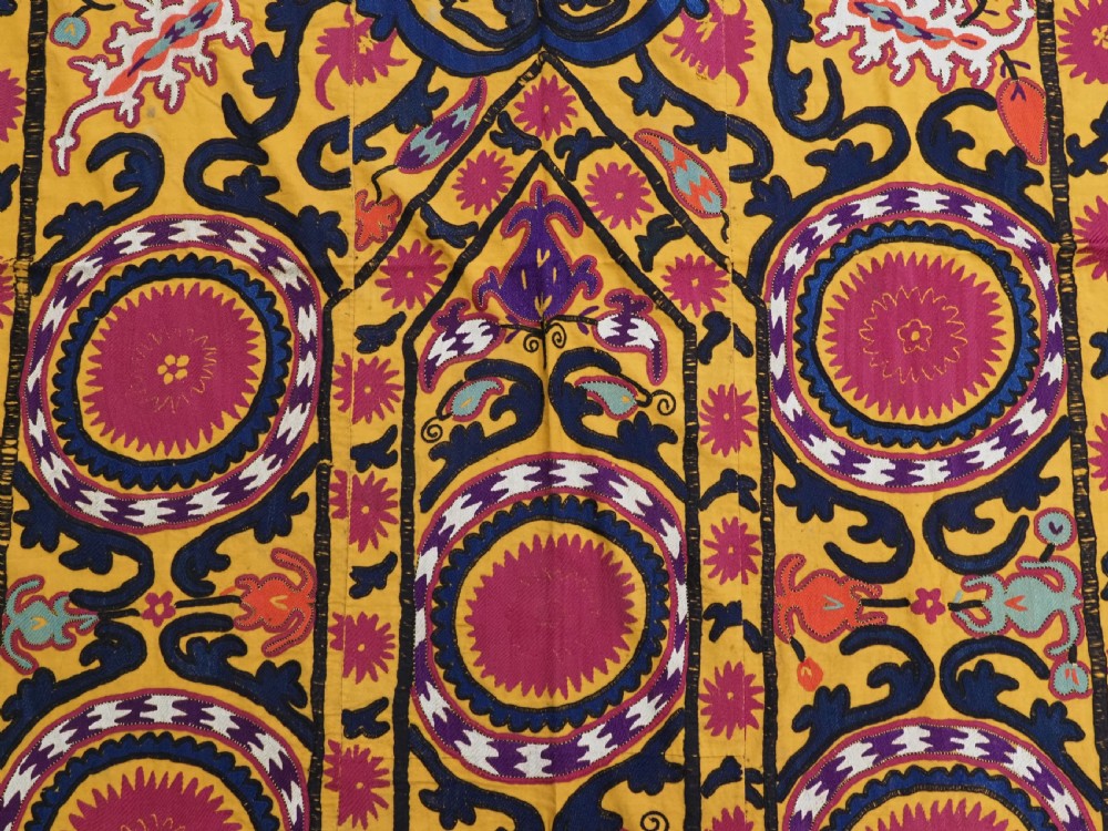 An antique Uzbek prayer suzani featuring silk embroidery with circular floral medallions and a central arch motif on a yellow cotton ground. View VII