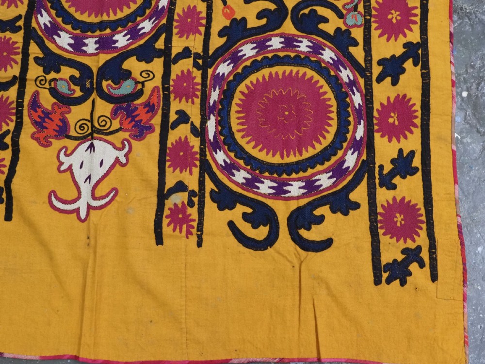 An antique Uzbek prayer suzani featuring silk embroidery with circular floral medallions and a central arch motif on a yellow cotton ground. View IX