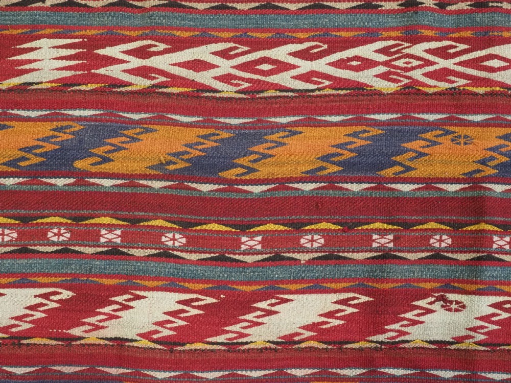An antique Central Asian Uzbek Gajeri flatweave kilim rug featuring horizontal bands of geometric motifs woven in red, ochre, navy, and cream wool with fringed ends. View IX
