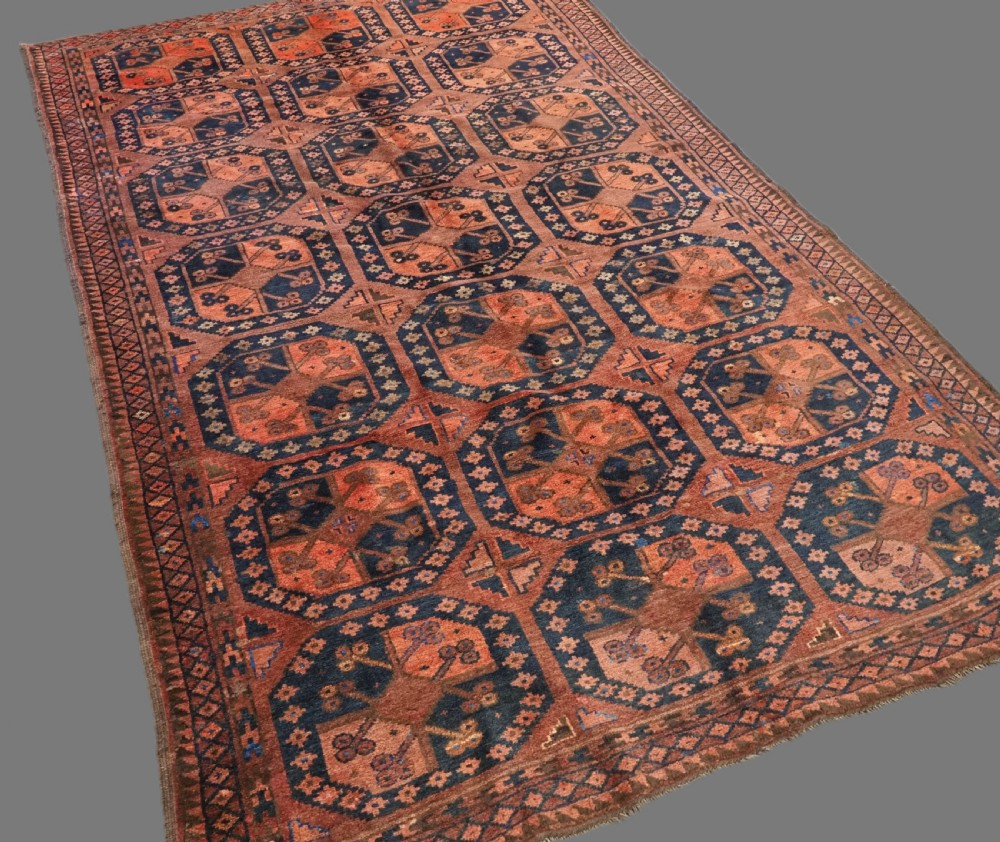 An antique hand-knotted Ersari Turkmen wool carpet featuring a repeated octagonal gul pattern in terracotta red, navy blue, and brown shades. View II