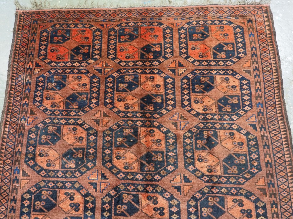 An antique hand-knotted Ersari Turkmen wool carpet featuring a repeated octagonal gul pattern in terracotta red, navy blue, and brown shades. View III