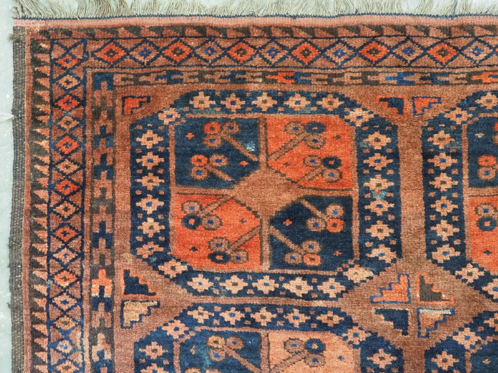 An antique hand-knotted Ersari Turkmen wool carpet featuring a repeated octagonal gul pattern in terracotta red, navy blue, and brown shades. View VI