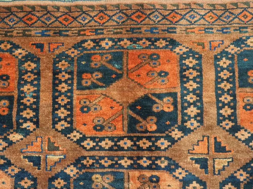 An antique hand-knotted Ersari Turkmen wool carpet featuring a repeated octagonal gul pattern in terracotta red, navy blue, and brown shades. View VIII