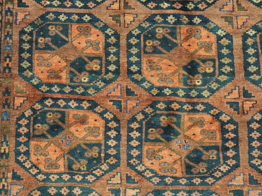 An antique hand-knotted Ersari Turkmen wool carpet featuring a repeated octagonal gul pattern in terracotta red, navy blue, and brown shades. View IX