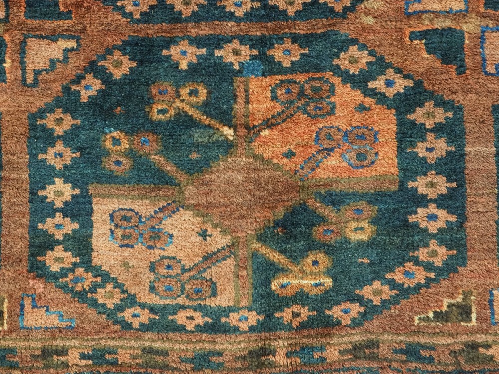 An antique hand-knotted Ersari Turkmen wool carpet featuring a repeated octagonal gul pattern in terracotta red, navy blue, and brown shades. View X