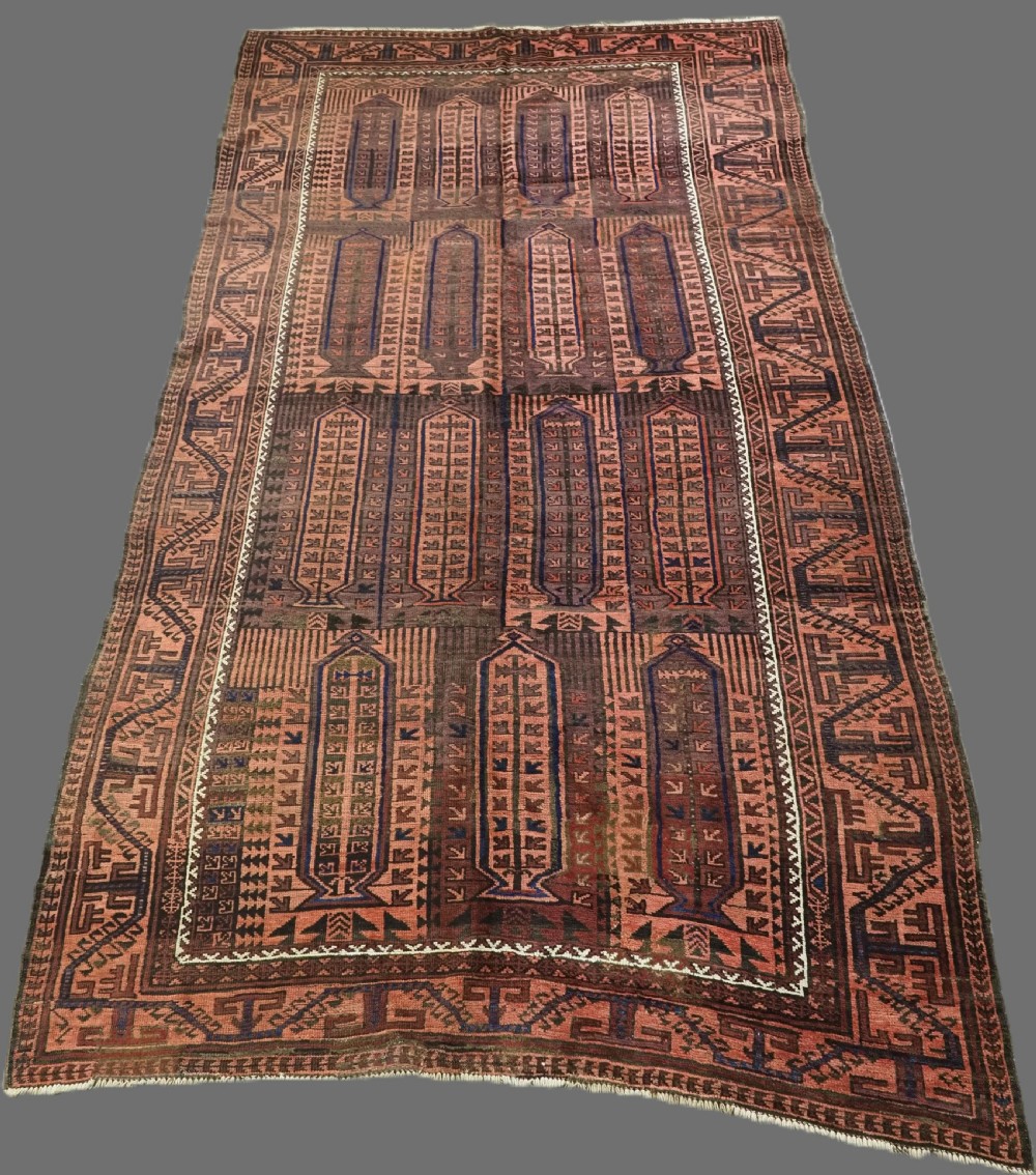 An antique hand-knotted wool carpet featuring a repeating kalam donneh pencil box pattern in shades of terracotta, dark brown, and indigo blue.