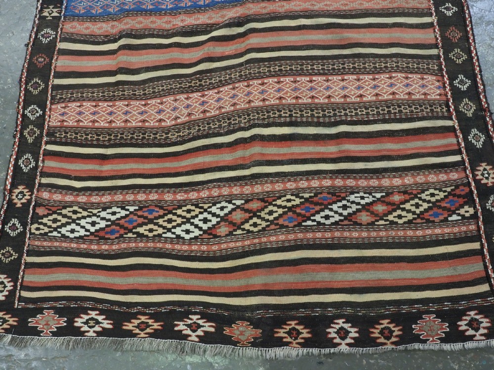 An antique handwoven Afghan Baluch kilim rug featuring horizontal geometric bands in red, blue, cream, and dark brown wool. View V