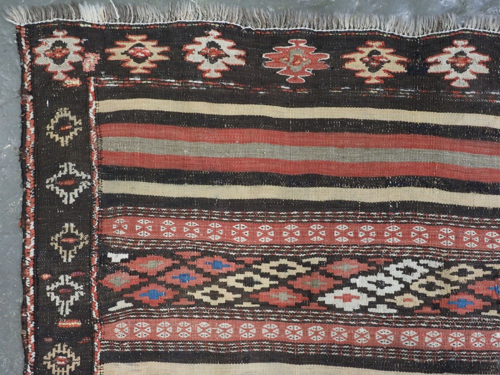 An antique handwoven Afghan Baluch kilim rug featuring horizontal geometric bands in red, blue, cream, and dark brown wool. View VI