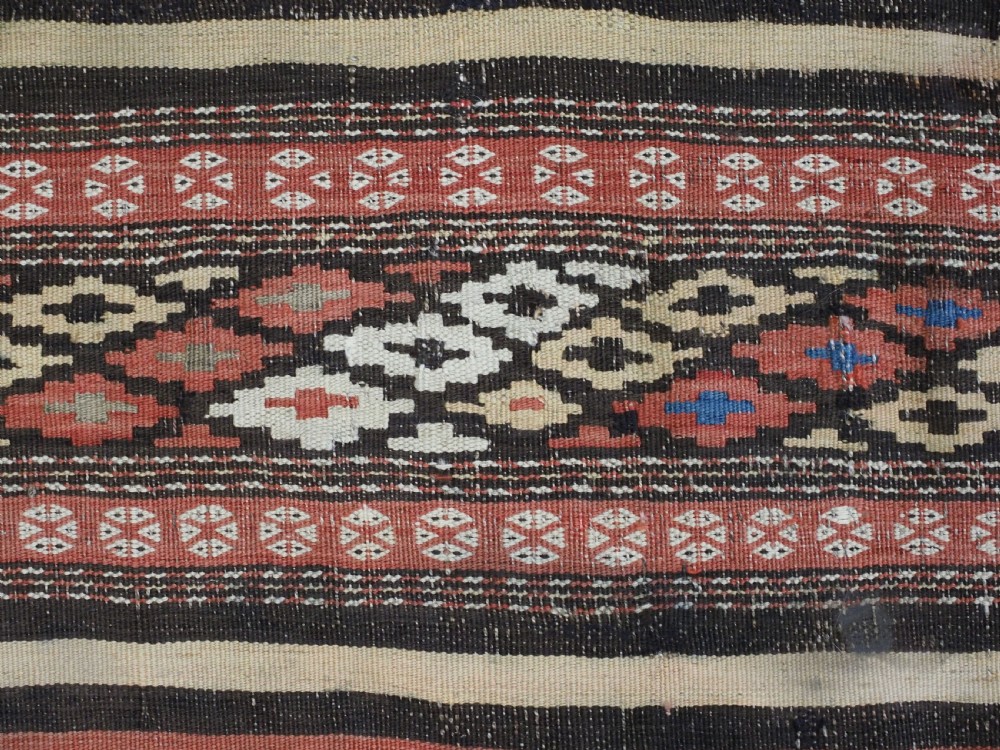 An antique handwoven Afghan Baluch kilim rug featuring horizontal geometric bands in red, blue, cream, and dark brown wool. View VIII