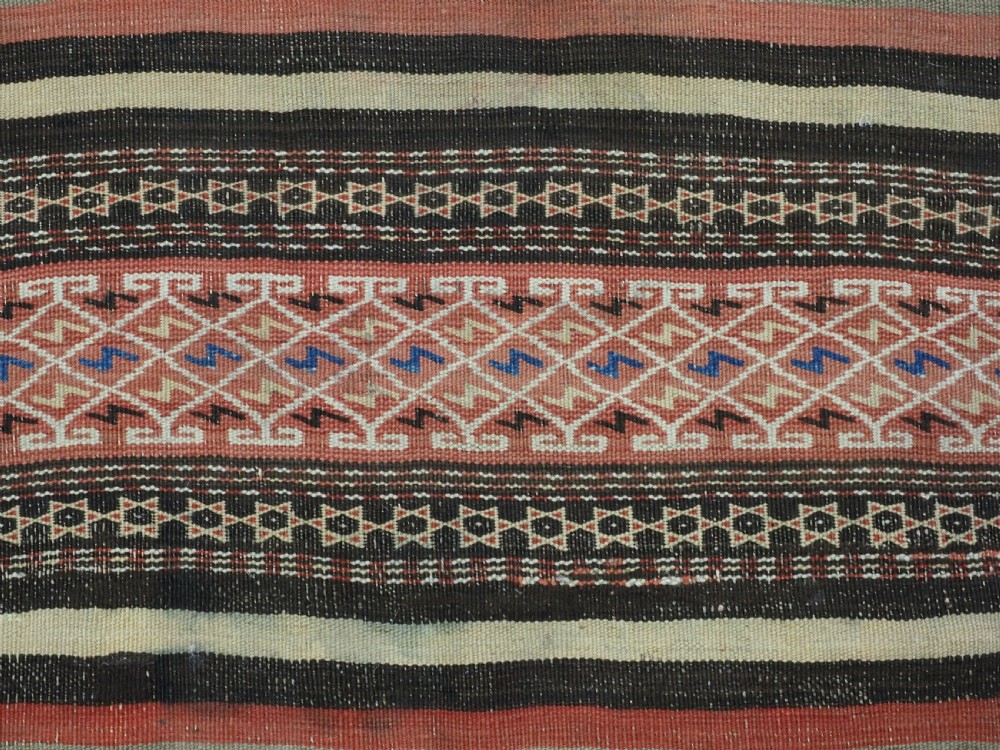 An antique handwoven Afghan Baluch kilim rug featuring horizontal geometric bands in red, blue, cream, and dark brown wool. View XI