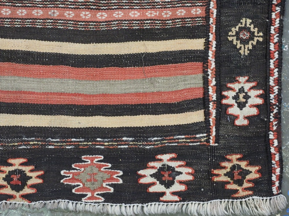An antique handwoven Afghan Baluch kilim rug featuring horizontal geometric bands in red, blue, cream, and dark brown wool. View XIII