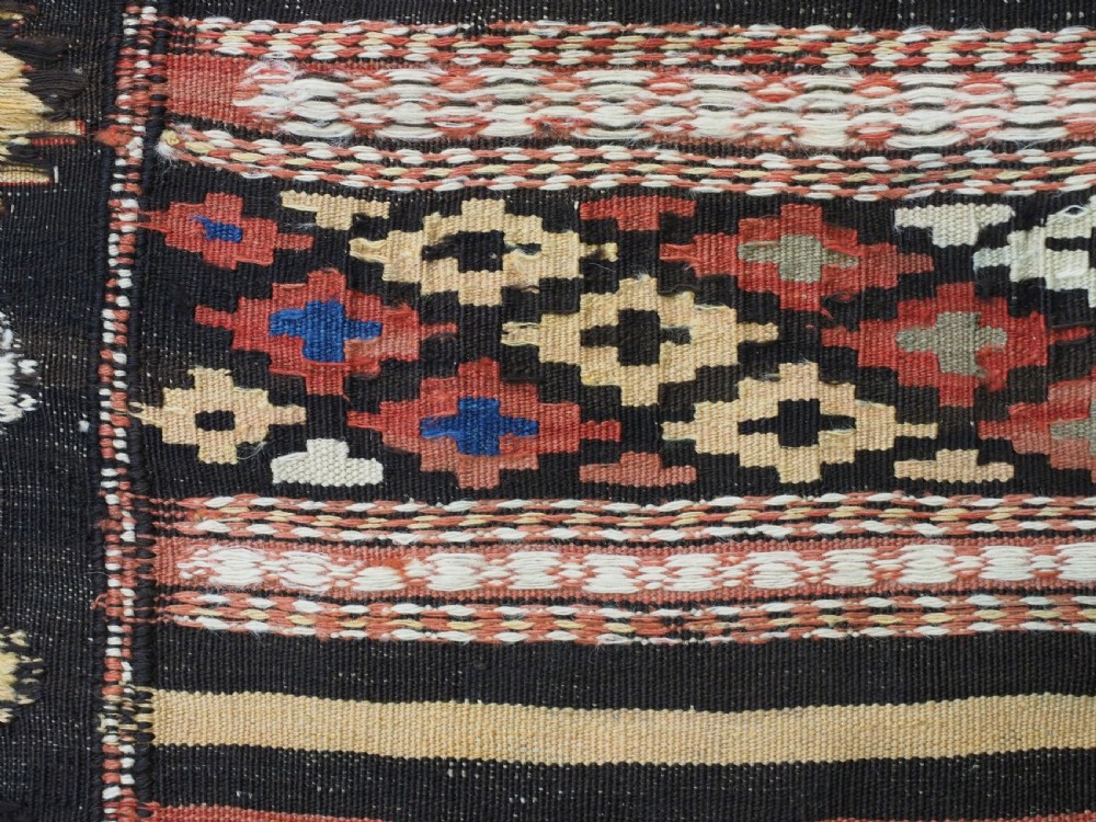 An antique handwoven Afghan Baluch kilim rug featuring horizontal geometric bands in red, blue, cream, and dark brown wool. View XIV