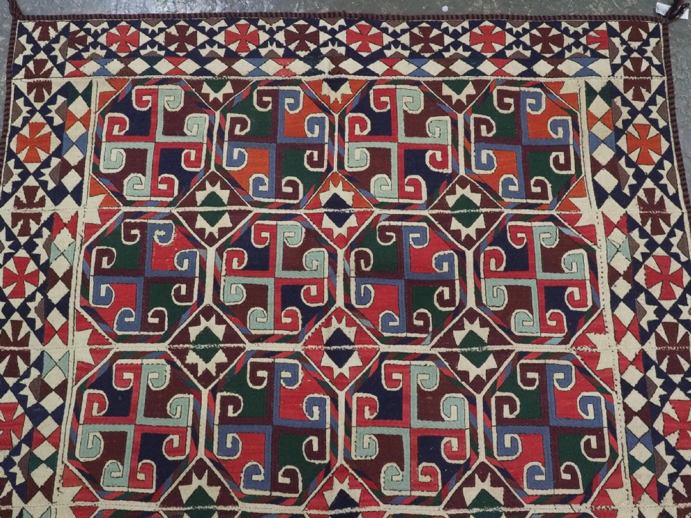 A rectangular antique Uzbek flatweave textile featuring repeating geometric octagonal medallions in red, green, blue, and cream with detailed motif borders. View IV