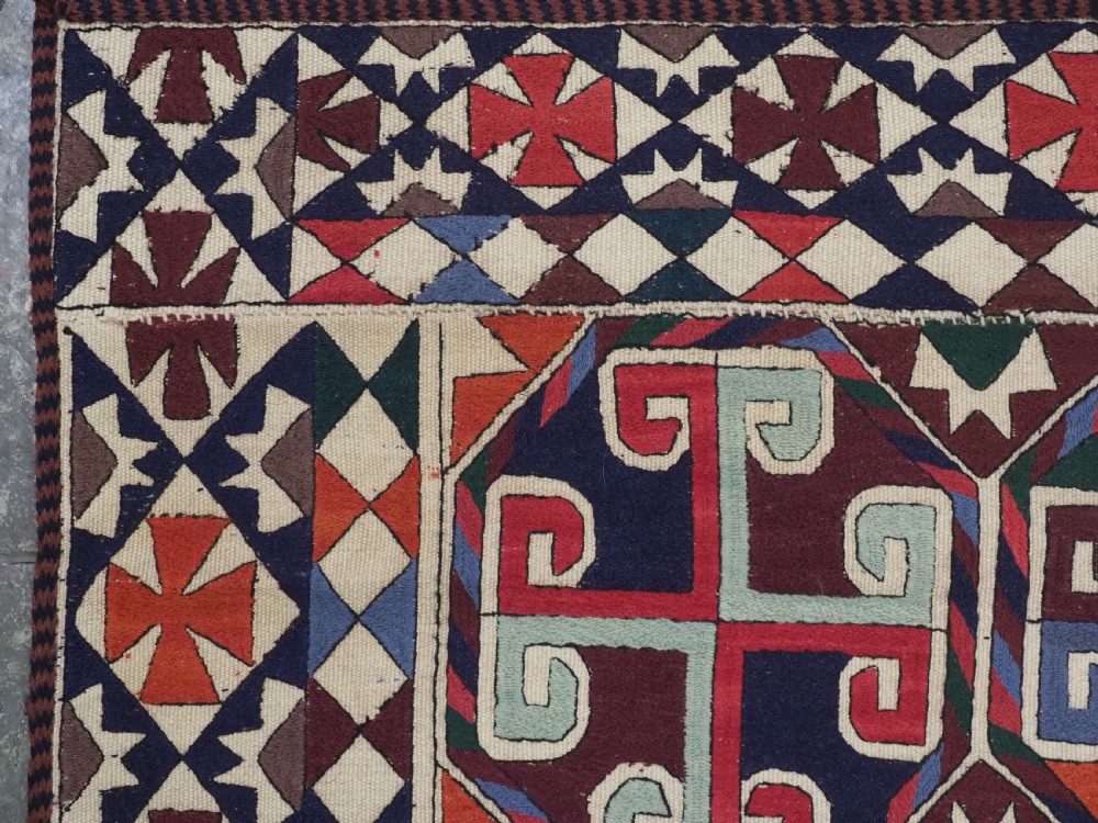 A rectangular antique Uzbek flatweave textile featuring repeating geometric octagonal medallions in red, green, blue, and cream with detailed motif borders. View VI