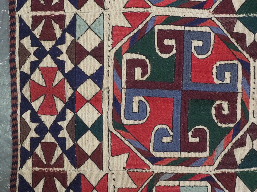 A rectangular antique Uzbek flatweave textile featuring repeating geometric octagonal medallions in red, green, blue, and cream with detailed motif borders. View VII