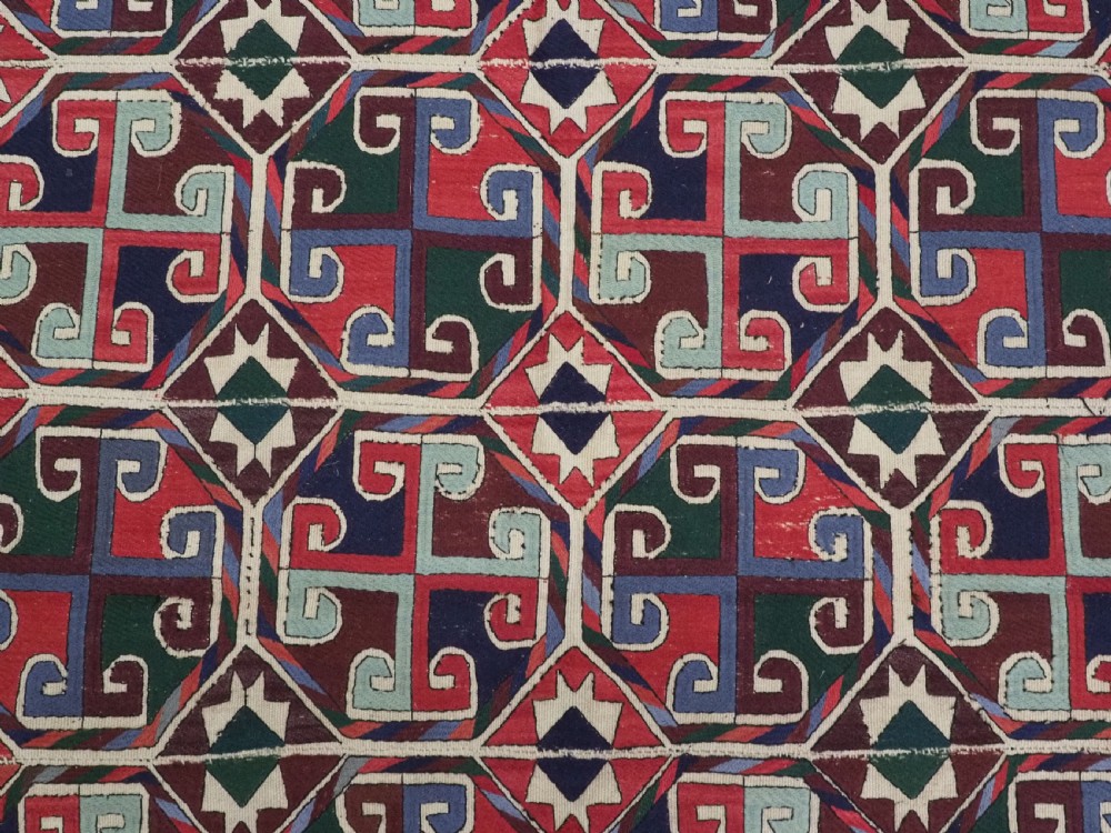 A rectangular antique Uzbek flatweave textile featuring repeating geometric octagonal medallions in red, green, blue, and cream with detailed motif borders. View IX