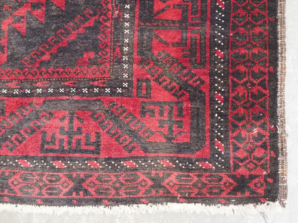 An antique Afghan Mushwani Baluch woven wool runner rug featuring deep crimson red and charcoal geometric diamond medallions along a narrow rectangular field with decorative borders. View XI