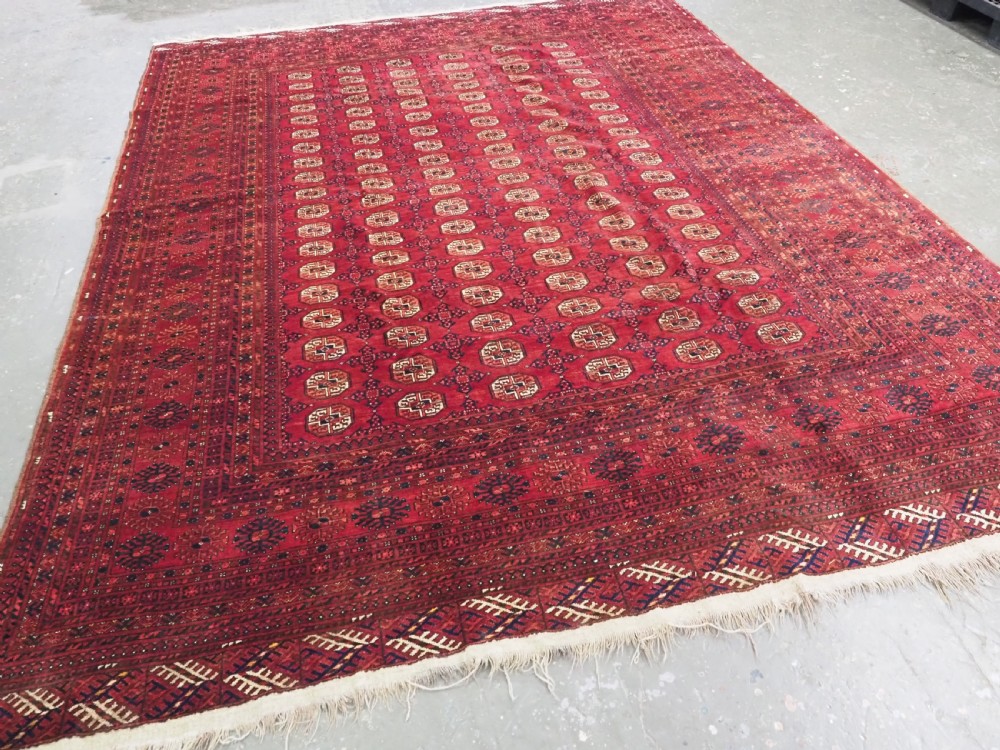 A large hand-knotted red wool carpet featuring repeated octagonal gul motifs across the central field with geometric borders. View II