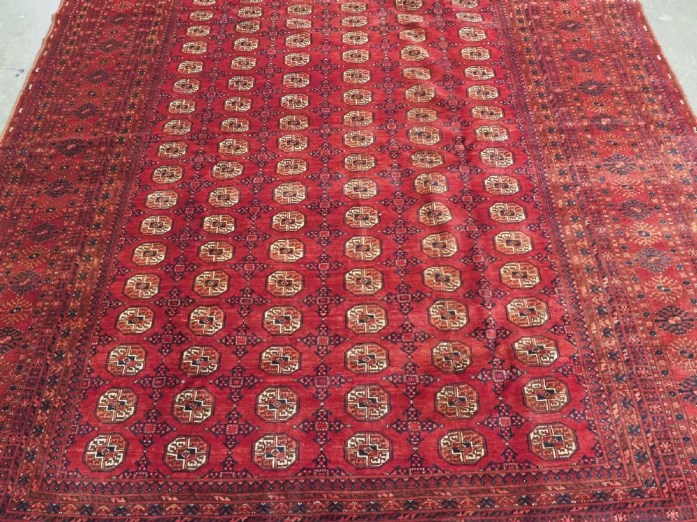 A large hand-knotted red wool carpet featuring repeated octagonal gul motifs across the central field with geometric borders. View IV