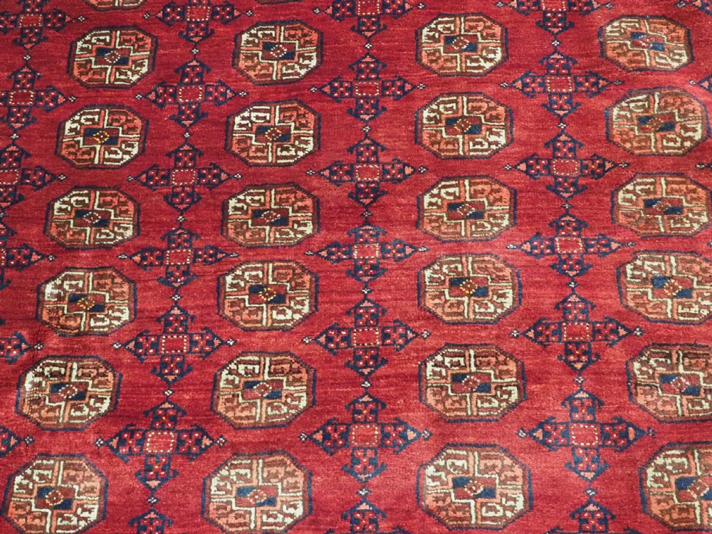 A large hand-knotted red wool carpet featuring repeated octagonal gul motifs across the central field with geometric borders. View XVI
