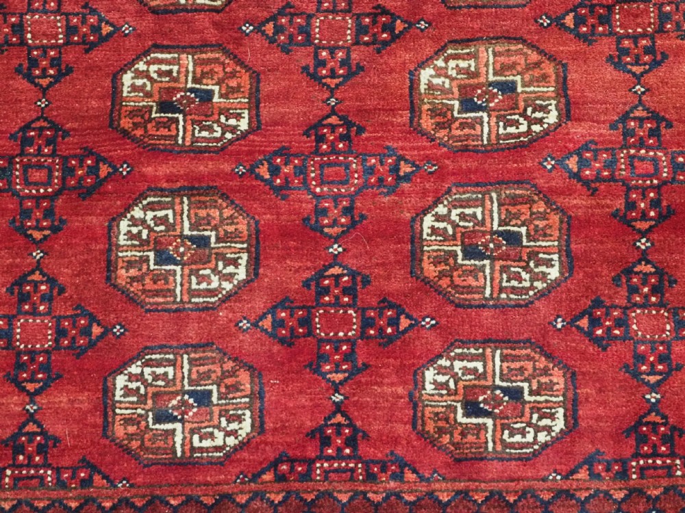 A large hand-knotted red wool carpet featuring repeated octagonal gul motifs across the central field with geometric borders. View XVII